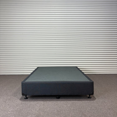 Charcoal fabric, bed base, made in New Zealand, pine wood, corner guard protection, on a gray floor with a striped wall background