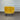 Yellow armchair with black legs against a corrugated metal wall.