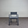 Gray chair with cushion against a corrugated metal wall.