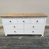 White dresser with wooden top on a gray floor against a beige wall