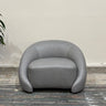 Gray armchair in a room with a plant on a wooden floor.