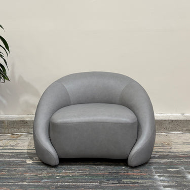 Gray armchair in a room with a plant on a wooden floor.