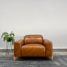 Brown leather armchair in a room with a plant and gray wall.