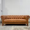 Brown leather sofa in a room with a plain wall.