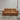 Brown leather sofa in a room with a plain wall and concrete floor.