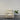 Beige armchair in a minimalistic room with a plant on a gray floor.