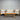 Outdoor furniture set with wooden table and beige cushions against a corrugated metal wall.