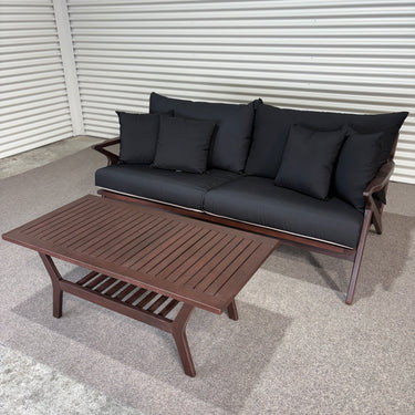 Outdoor furniture set with a sofa and coffee table on a concrete floor.