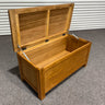 Wooden storage chest with open lid on a gray floor.