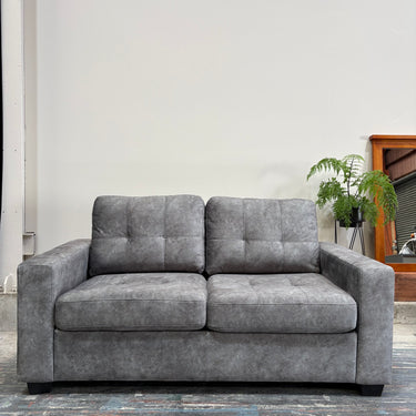 Gray sofa in a room with a plant and wooden cabinet.