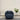 Blue armchair in a room with a plant on a stand against a plain wall.