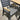 Gray chair with wooden armrests and seat cushion next to a wooden table on a concrete floor.