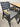 Gray chair with wooden armrests and seat cushion next to a wooden table on a concrete floor.