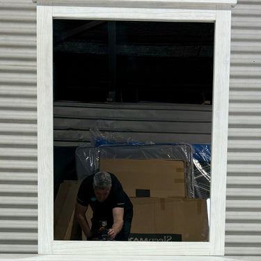 Person working with boxes and plastic sheeting inside a building reflected in a window.