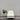 White armchair with a plant against a gray wall