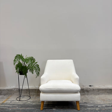 White armchair with a plant against a gray wall
