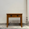 Wooden console table with two drawers against a plain wall.