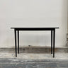 Black table against a plain wall on a wooden floor