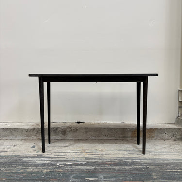 Black table against a plain wall on a wooden floor
