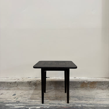 Black square table against a plain white wall.