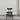 Black chair with gray cushion on a concrete floor against a white wall.