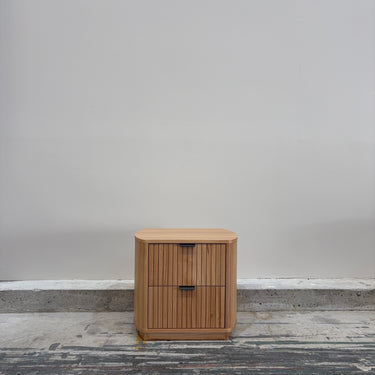 Wooden cabinet with two drawers on a concrete floor against a gray wall