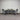 Dining table with four chairs against a corrugated metal wall.