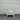 White chair with gray cushion against a corrugated metal wall.