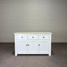 White sideboard with a wooden top against a corrugated metal wall. Kinloch Colletion