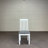 White chair with a gray cushion against a corrugated metal wall. Kinloch Collection