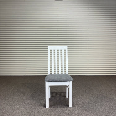 White chair with a gray cushion against a corrugated metal wall. Kinloch Collection