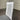 White wooden chair with a gray cushion on a gray floor against a corrugated metal wall. Kinloch collection