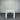 White table with a light wooden top against a corrugated metal wall.