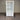 White cabinet with glass doors and drawers against a corrugated metal wall.