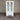 White cabinet with glass doors and a drawer on a gray floor against a corrugated metal wall.