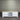 White wooden TV stand with a marble top against a corrugated metal wall.