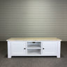 White wooden TV stand with a marble top against a corrugated metal wall.