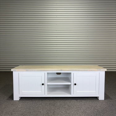 White wooden TV stand with a marble top against a corrugated metal wall.