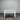 White wooden console table with two drawers against a corrugated metal wall.