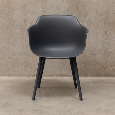 Dark gray chair with black legs against a beige wall.