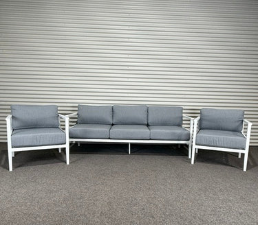 Outdoor furniture set with gray cushions on a metal wall background