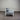 White chair with gray cushions against a corrugated metal wall.