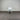 White chair with a gray cushion against a corrugated metal wall.