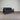 Black sofa with cushions against a corrugated metal wall.