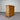 Wooden dresser with four drawers against a corrugated metal wall.