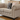Beige sofa with decorative pillows on a wooden floor in a room with a dresser.