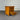 Wooden nightstand with two drawers, one open, against a corrugated metal background.