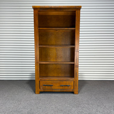 Wooden bookshelf with a drawer against a corrugated metal wall. wanaka collection