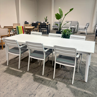 Outdoor dining table and six chairs in matte white anodised aluminium with Retreat Grey cushions, Mantra collection.