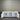 White storage cabinet with open doors against a corrugated metal wall.
